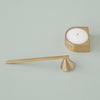 Gold candle holder and snuffer on a soft green background, showcasing sleek geometric shapes and smooth finishes.