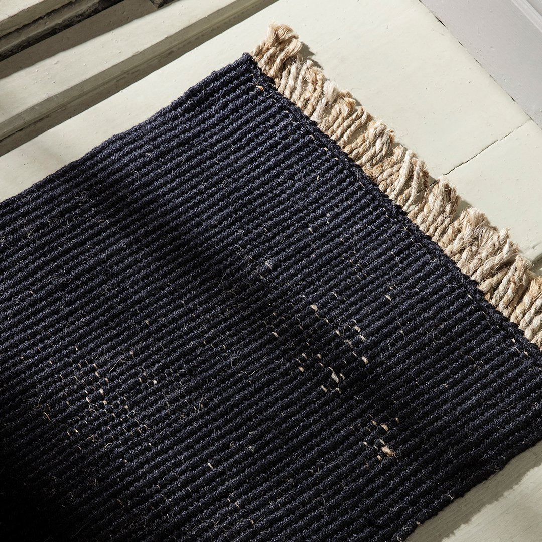 Navy blue woven rug with beige fringes, showcasing a textured striped pattern. Perfect for modern decor.
