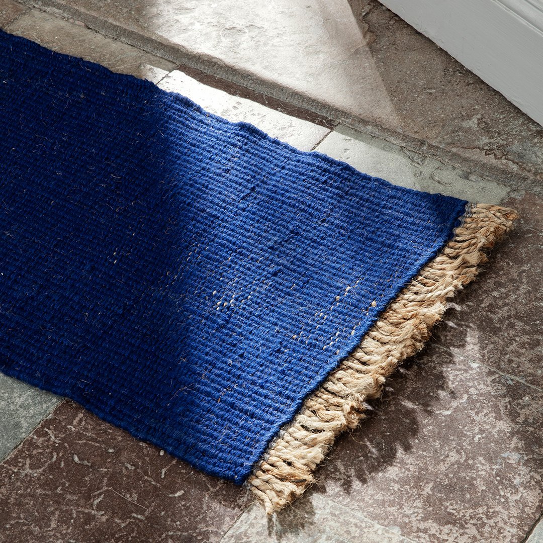 Textured navy blue rug with a natural fringe edge, perfect for adding a pop of color to any room.