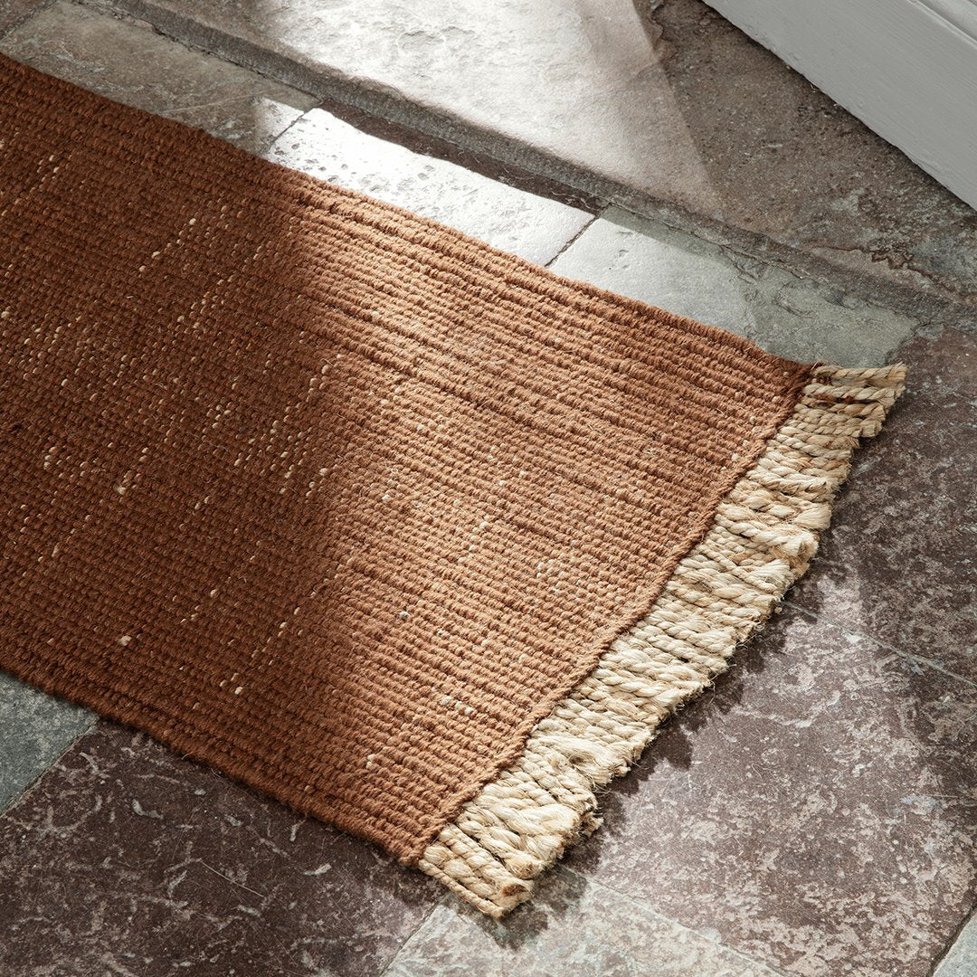Brown woven rug with subtle texture and fringe in a warm, earthy tone. Perfect for cozy home decor.