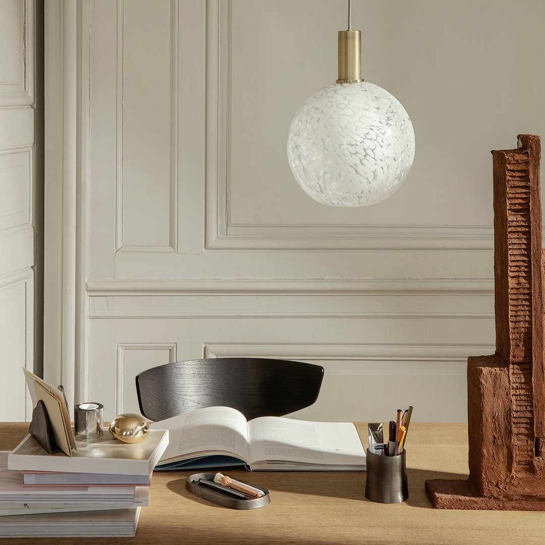 White textured glass pendant lamp with gold accents, illuminating a stylish workspace. Elegant and modern design.