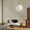 White textured globe pendant light with gold accents, surrounded by a neutral color palette and natural materials.