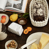 Rustic wooden table with a mix of earthy tones, soft neutrals, and pops of yellow and orange from food items.