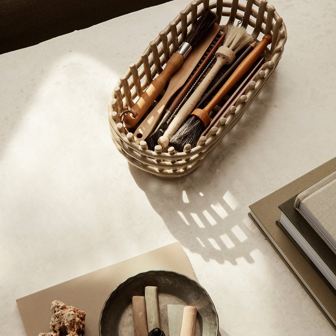 Woven beige basket with wooden utensils, set against a neutral background and soft light, showcasing minimalistic design.