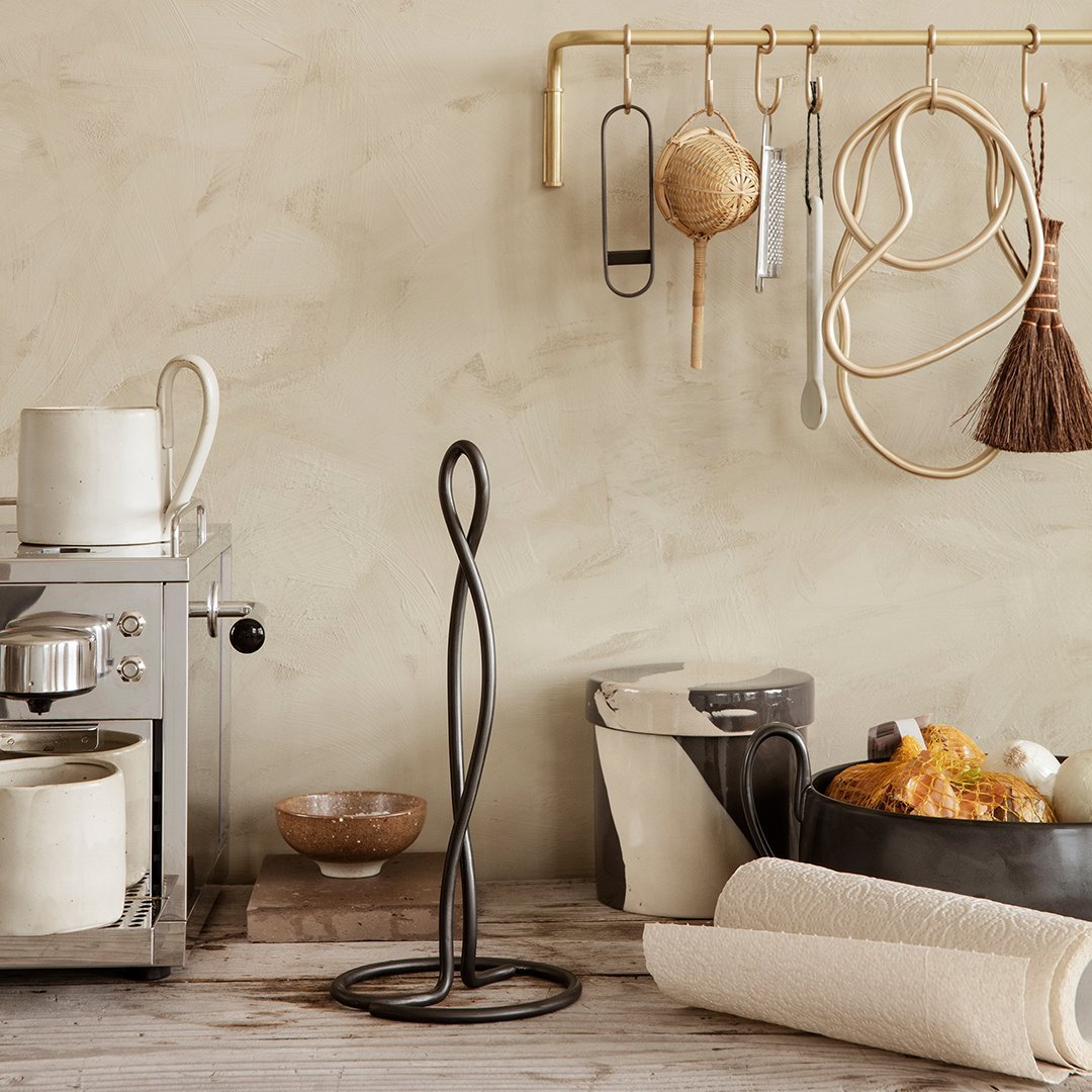 Black wire kitchen accessory on a neutral beige backdrop with wooden and metallic accents in a contemporary kitchen setting.