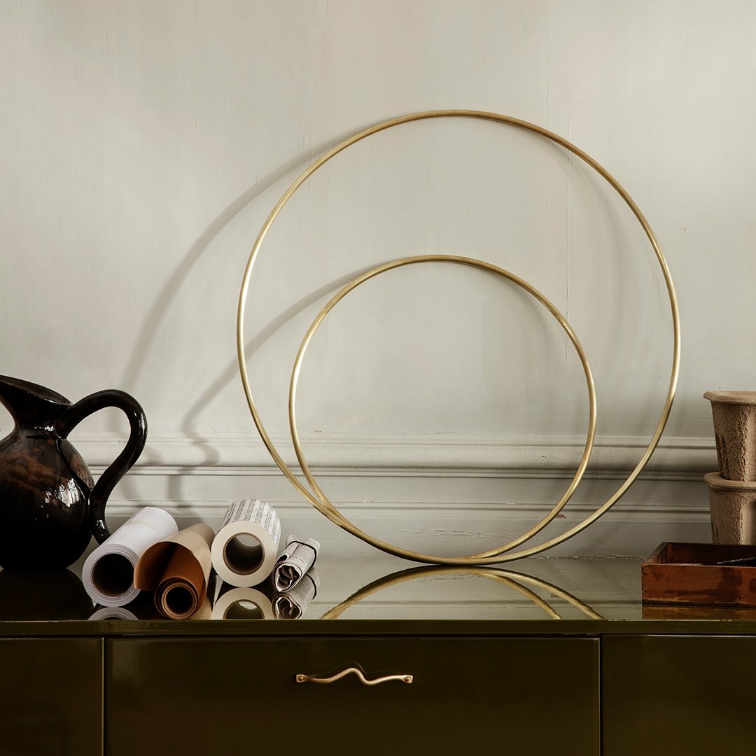 "Gold circular decorative accents against a neutral wall, surrounded by brown and cream rolled paper prints."