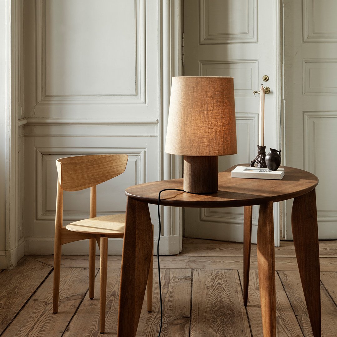 Natural wood table and chair with a textured beige lamp, featuring warm tones and minimalist design.
