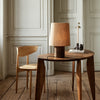 Natural wood table and chair with a textured beige lamp, featuring warm tones and minimalist design.