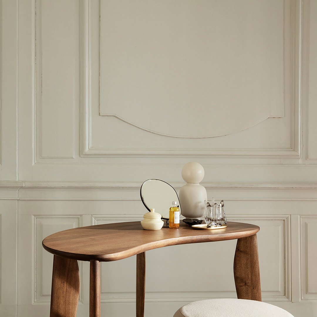 Natural wood table with smooth curves, complemented by soft white accessories and a minimalist, neutral backdrop.