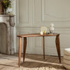Elegant walnut table with smooth curves, showcasing rich brown tones and a minimalist design against a neutral backdrop.