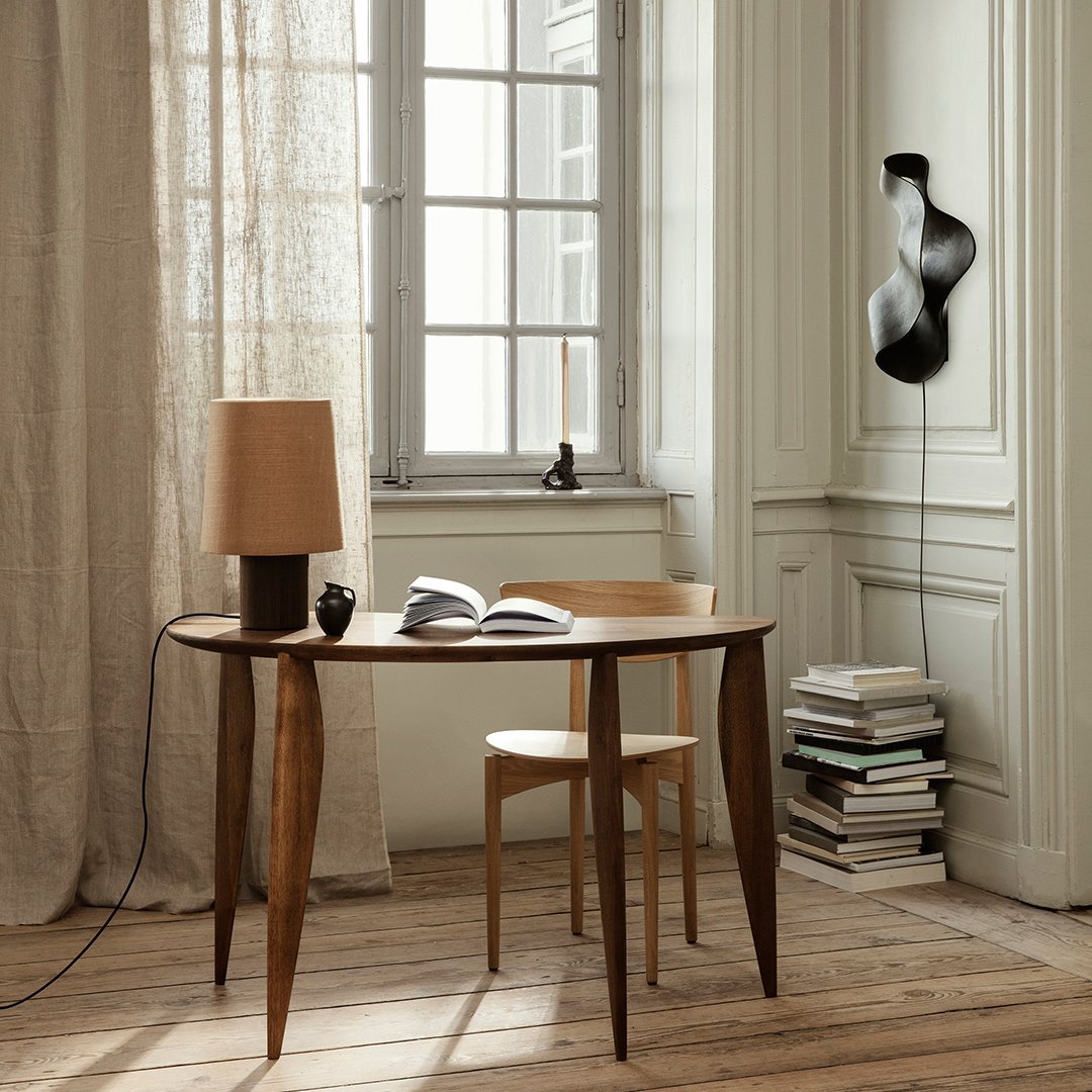 "Warm wood tones, beige lampshade, and neutral curtains create a cozy, minimalist interior setting."
