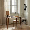 "Warm wood tones, beige lampshade, and neutral curtains create a cozy, minimalist interior setting."