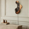 Abstract wall lamp with a sleek black and copper finish, featuring smooth curves and modern lines.