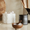 Neutral-toned kitchenware with white stone, dark ceramic, and wooden textures, featuring rustic, natural patterns.