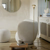 Modern beige and cream decor with a minimalist gold floor lamp in a cozy, neutral-toned living space.