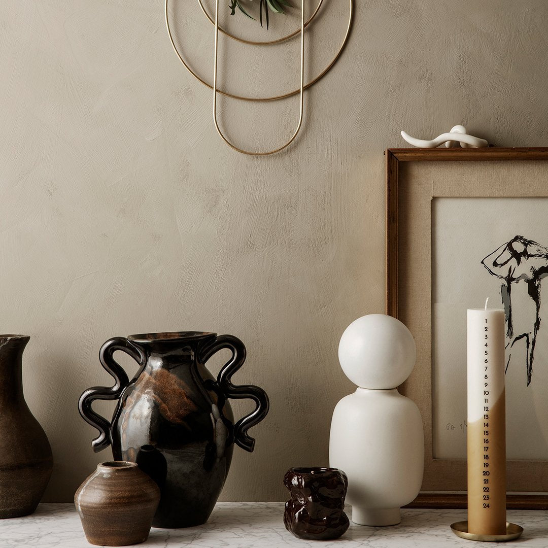 "Collection of earthy tones and unique patterns in vases and decor, featuring dark brown, white, and neutral hues."