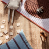 Colorful play mat featuring organic shapes in brown, white, and soft pastels on a textured natural backdrop.