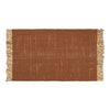 Rust-colored woven rug with fringe edges, featuring a textured, subtle pattern. Perfect for warm home decor.