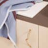 Textured blue and maroon striped fabric draped over a beige surface with a gold handle, creating a stylish contrast.