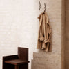 Light beige trench coat hanging against a textured beige wall, showcasing a minimalist design without patterns.