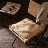 Brown textured seat cushion on a minimalist black chair; warm, neutral tones create a cozy atmosphere.
