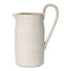 Cream-colored ceramic pitcher with a smooth, matte finish and subtle speckles. Elegant, minimalist design.