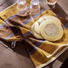 Brown and yellow plaid kitchen towel with circular cream-colored plates, featuring a glossy finish and minimal water droplets.