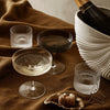 "Elegant glassware in clear, smoky black, and frosted finishes on a rich brown fabric backdrop."