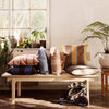 Multicolored striped cushions in shades of blue, brown, and yellow arranged on a wooden bench.