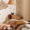Cozy bedding in warm browns, beige, and soft pastels with playful patterns and textured accents in a stylish room.