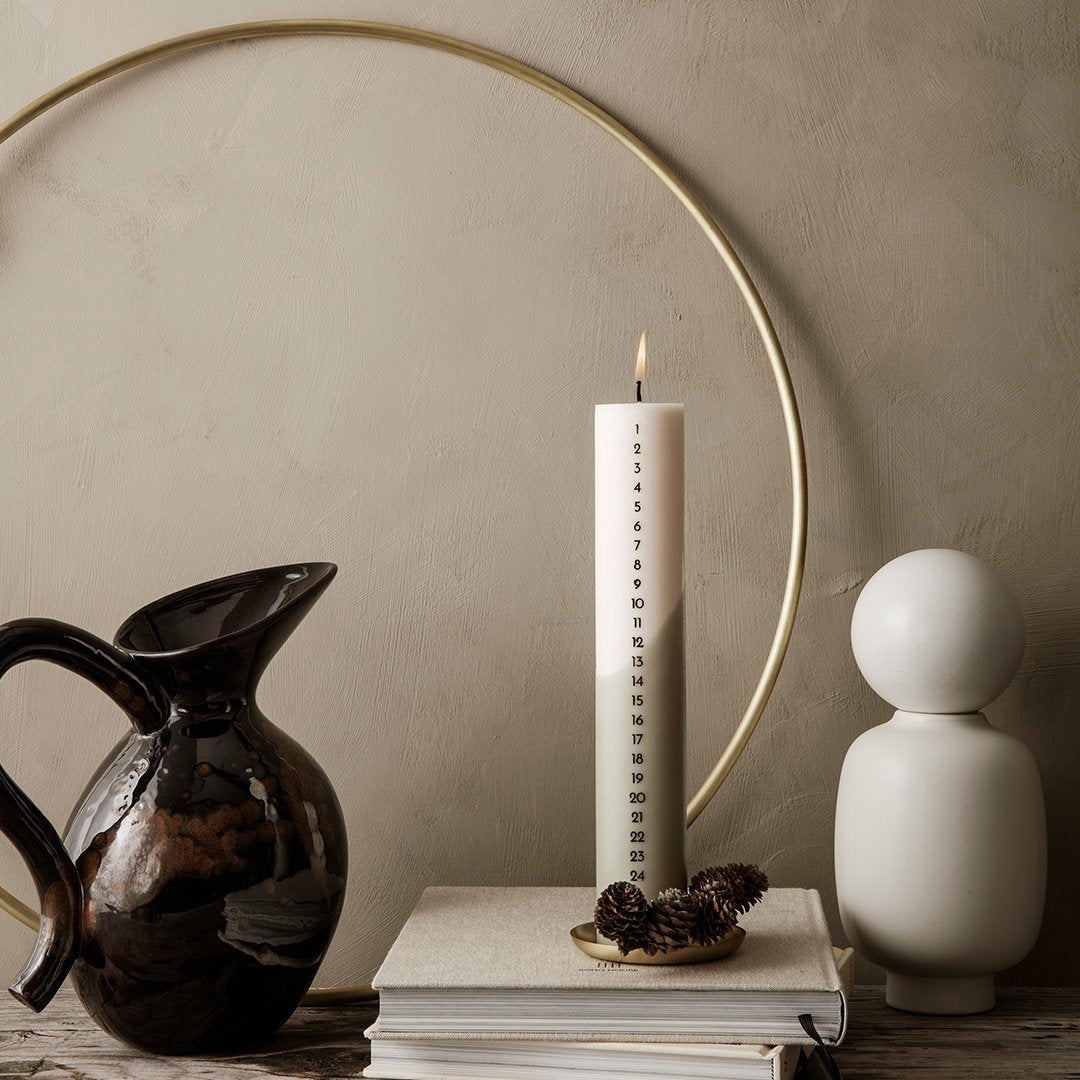 Modern decor with a sleek white candle, black ceramic jug, and white accent statue against a neutral backdrop.