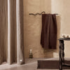 Striped beige and white curtains alongside a solid dark brown towel, set against a warm, textured wall.